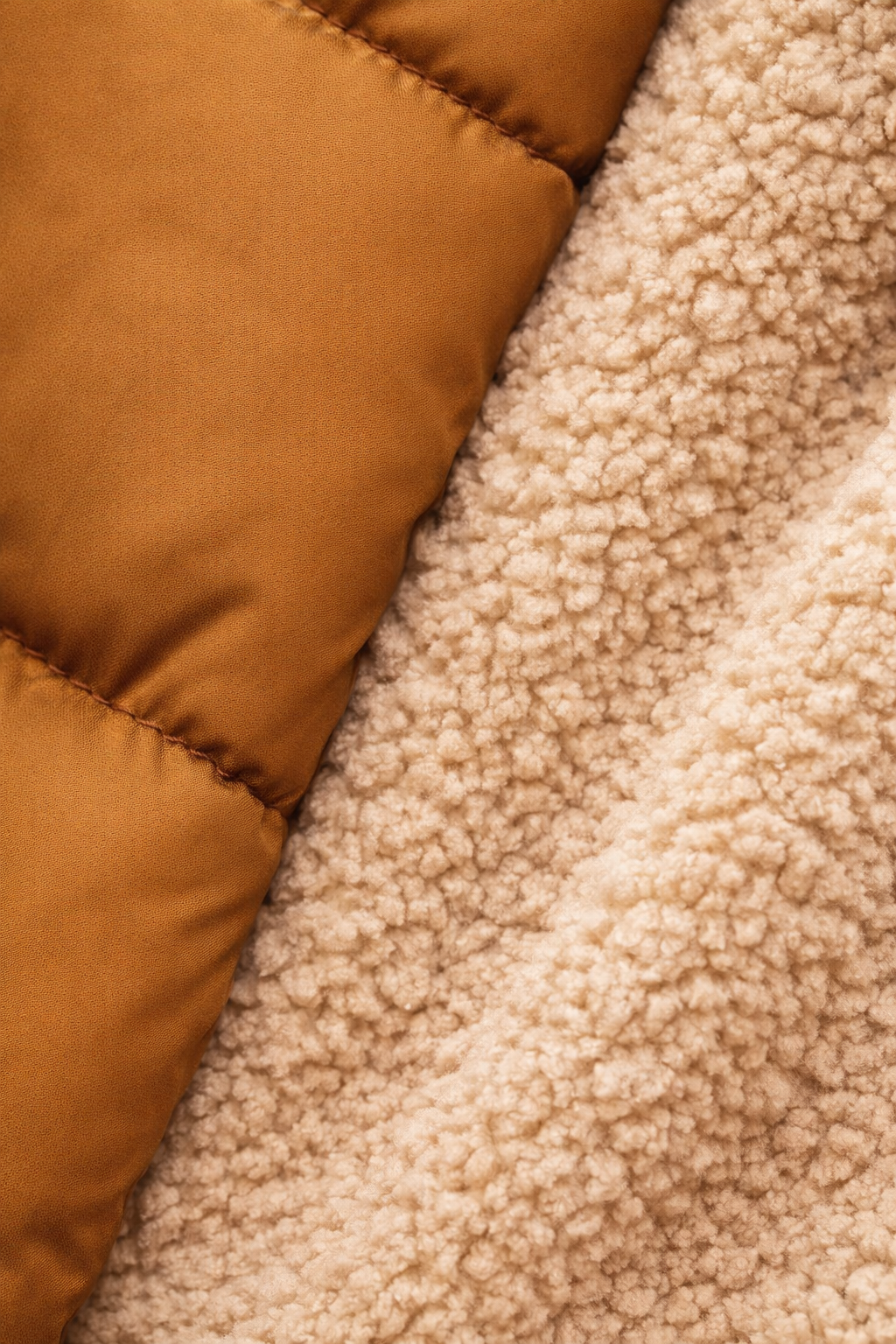 Detailfoto van de gewatteerde stof en teddyvoering in camel